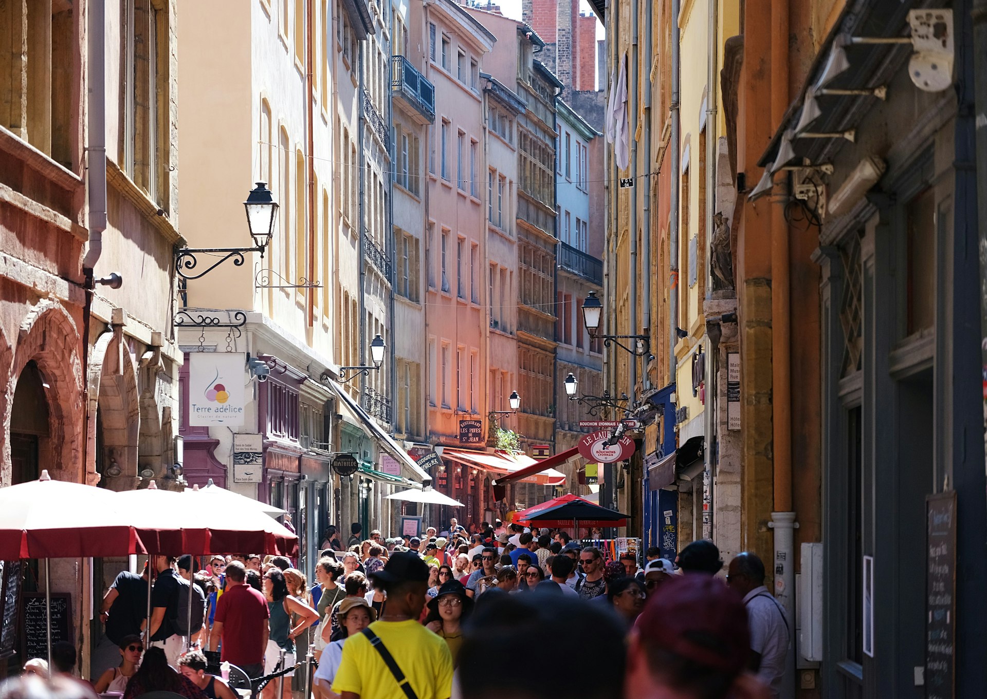 a crowd of people walking down a street next to tall buildings