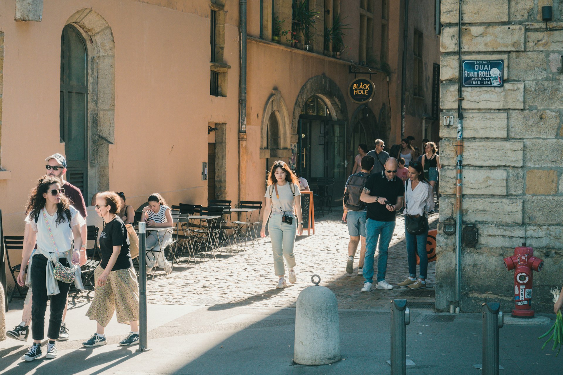 A group of people walking down a street next to tall buildings